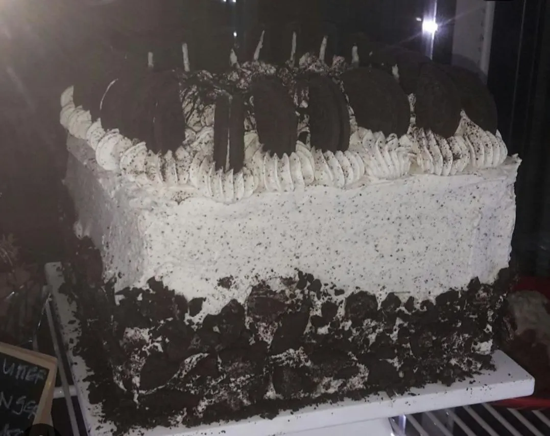 A cookies and cream cake covered in crushed cookies and topped with whole ones