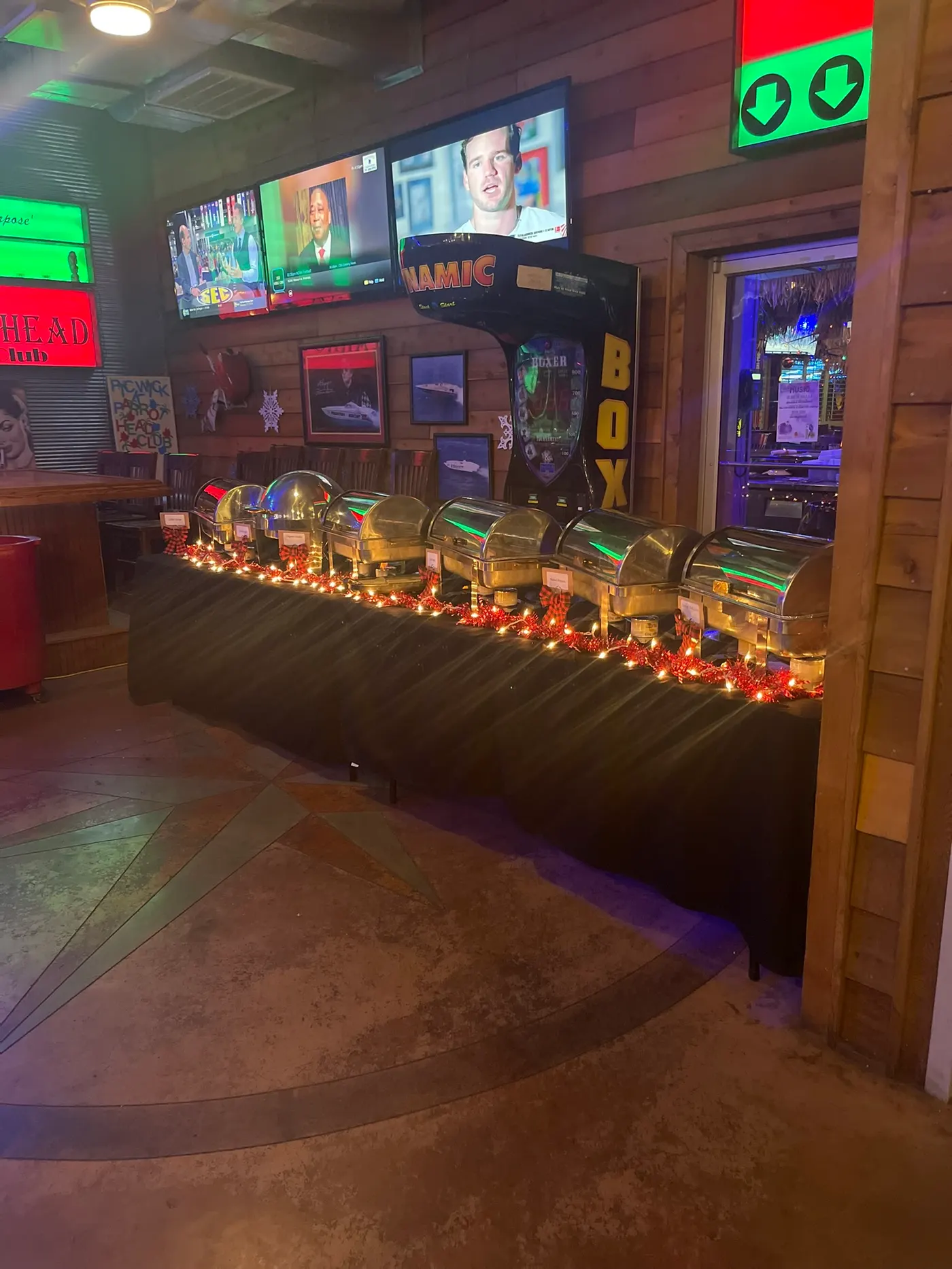 A buffet line of chafing dishes strung with fairy lights, set up beneath the arcade machines in Club 50
