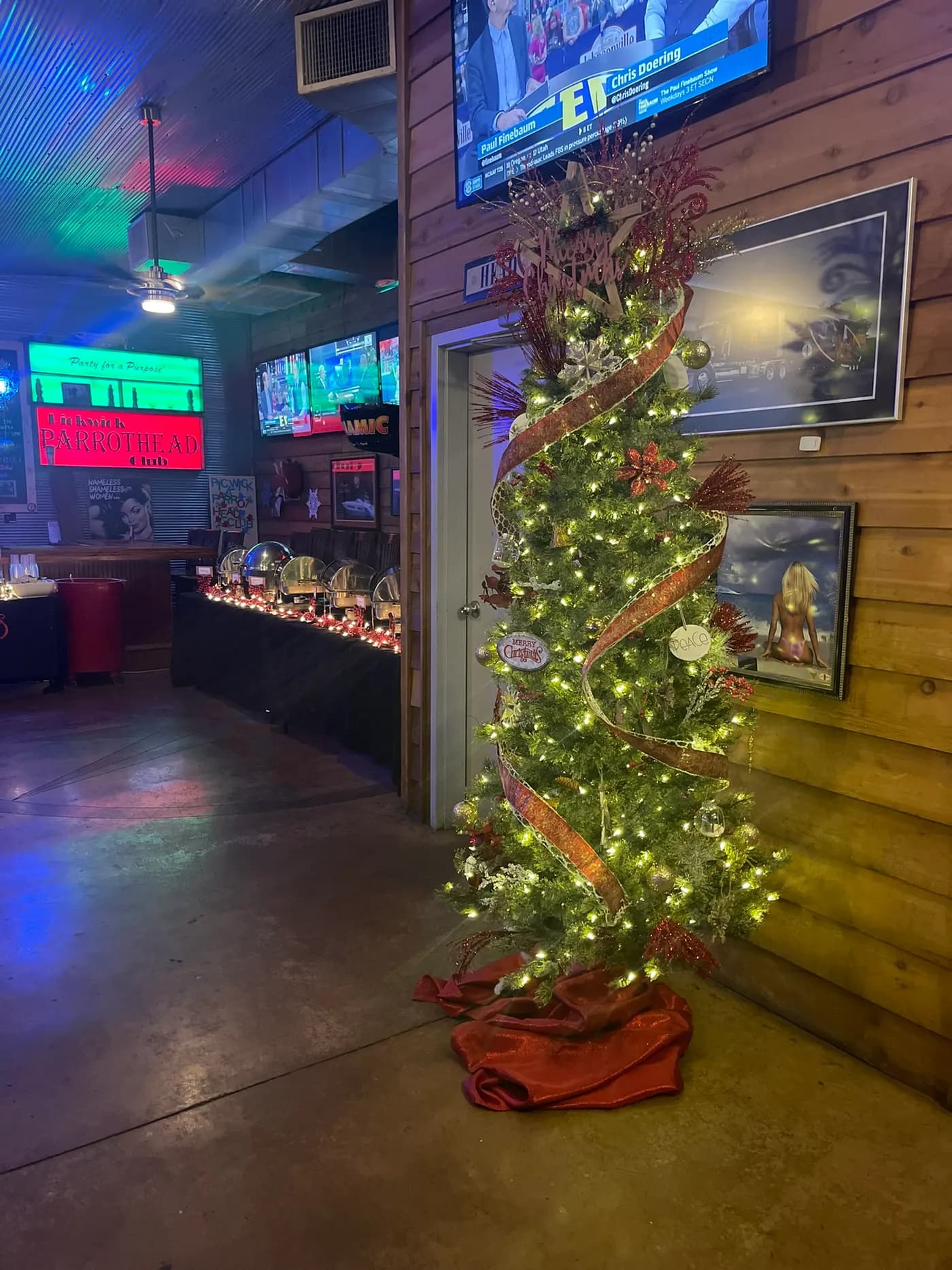 A lit Christmas tree standing beside a dessert table in the corner of the room