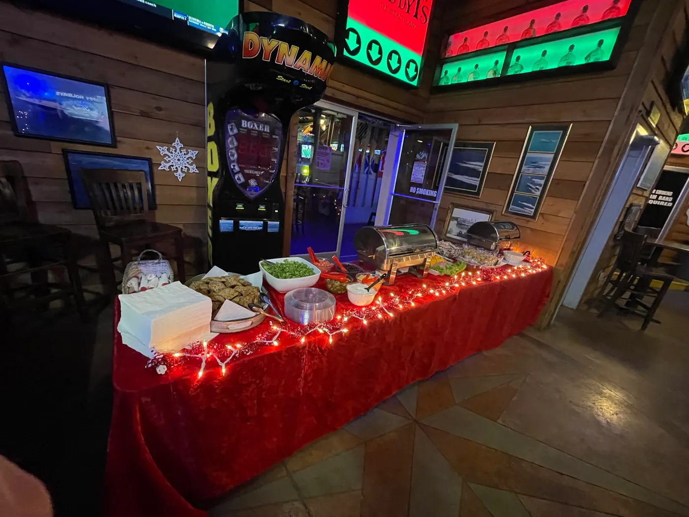 A red-clothed buffet table of salads and sides, under the arcade cabinets