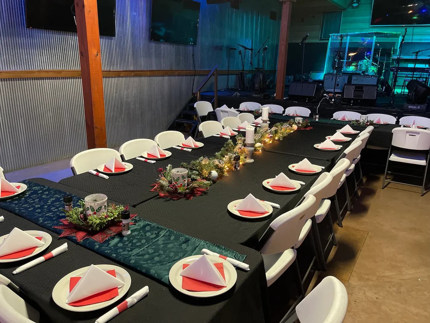 Tables laid with place settings and greenery, the stage lit behind them