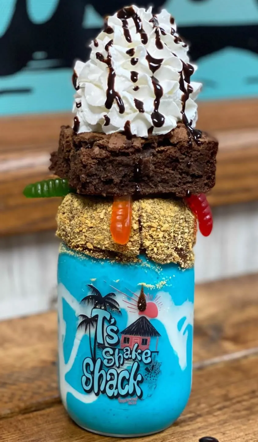 A brownie milkshake stacked with whipped cream, gummy sweets and a chocolate bar