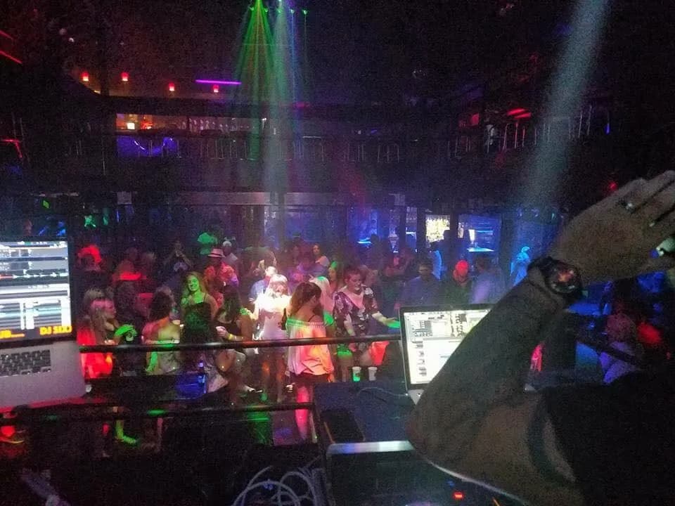 A DJ playing to a packed dance floor under green lasers at the Beach Club